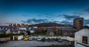 a city with cars parked in a parking lot at The Castle Hotel, Conwy, North Wales - The Coaching Inn Group in Conwy