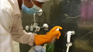 a person wearing a mask and gloves washing a sink at Panthashala Santiniketan in Srī Niketan