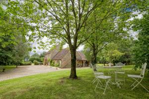 a table and chairs under a tree in a yard at Great Ashley Farm Holiday Cottage & Shepherds Huts in Bradford on Avon
