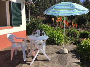 einen Tisch, zwei Stühle und einen Regenschirm in der Unterkunft Bungalows Do Amparo in Ponta do Pargo