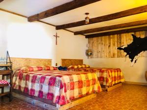 a bedroom with two beds and a cross on the wall at Cabañas el Pajar in Zacatlán