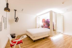 1 dormitorio con 1 cama blanca y 1 silla roja en Qbic Amsterdam WTC en Ámsterdam