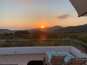 puesta de sol desde un balcón con sillas y mesa en Mare Natura, en Castelsardo