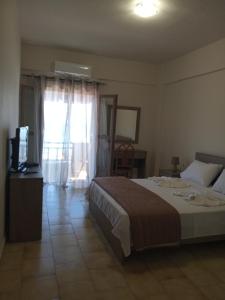 a bedroom with a bed and a television and a window at Buganvilla Sea View apts in Agia Pelagia