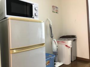 a microwave on top of a refrigerator in a kitchen at 駅南うちやまビルさん in Fukuoka