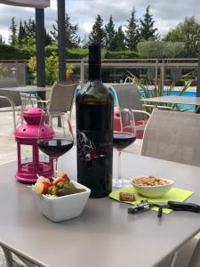 una botella de vino y un tazón de comida en una mesa en Logis Hôtel Restaurant Les Aubuns en Caissargues