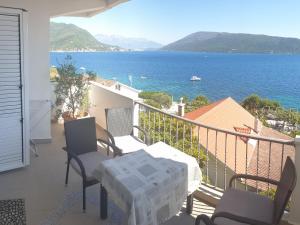 a balcony with a table and chairs and the ocean at Apartments Miljevic in Herceg-Novi