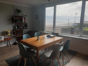 a table and chairs in a room with a view of the beach at Eastwatch guesthouse in Berwick-Upon-Tweed