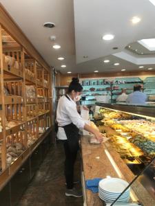a woman is preparing food in a bakery at Pine Apartment - a 3m da ciclovia Guincho in Cascais