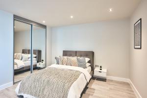 a bedroom with a large bed and a mirror at Seven Living Bracknell - Serviced Apartments in City Centre - Free Parking in Bracknell