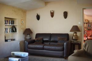 a living room with a leather couch and a book shelf at Maison du Loup in Ganges