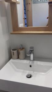 a bathroom sink with a faucet and two cups on it at iliolithos rooms in Kardamili