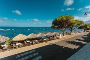 a beach with chairs and umbrellas and the ocean at Hotel Ristorante La Conchiglia in Cala Gonone