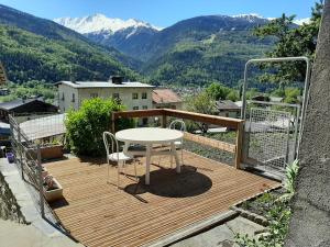 uma mesa e cadeiras num deque de madeira com montanhas em La Maison Trésallet em La Plagne Tarentaise