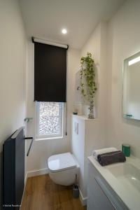 baño con aseo y lavabo y ventana en L'île de la Brèche, en Niort