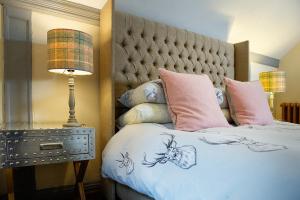 a bedroom with a large bed with pink pillows at The Falls Of Dochart Inn in Killin