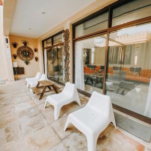 Habitación con sillas blancas, mesas y ventanas. en Mina Al Fajer Villas, en Wāsiţ