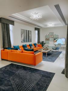 a living room with an orange couch and a table at Mina Al Fajer Villas in Wāsiţ