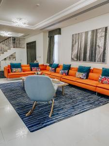 a living room with orange couches and a blue couch at Mina Al Fajer Villas in Wāsiţ