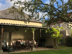 ein Haus mit einer Terrasse mit einem Tisch und Stühlen in der Unterkunft Le petit clos du Bessin in Longues-sur-Mer