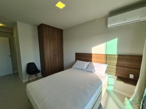 a bedroom with a bed and a chair in it at PORTO AZUL - Praia do Forte - Apart in Cabo Frio