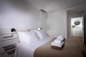 Un dormitorio con una cama blanca con toallas. en The Wish São Roque en Ponta Delgada