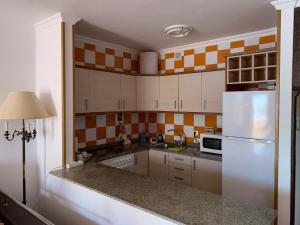 a kitchen with a white refrigerator and orange and white tiles at Apartamento Muelle de Corralejo 14 in Corralejo