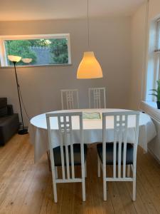 a white dining room table with two chairs and a lamp at Anne's Bed & Kitchen, Dalgaard in Horsens