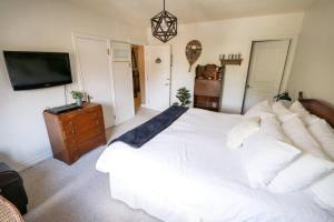 a bedroom with a white bed and a television at Banff Mountain Home- The Real Rockies Experience in Banff