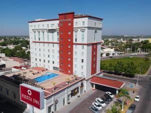 a hotel with a red and white building with a pool at Fiesta Inn Ciudad Obregon in Ciudad Obregón
