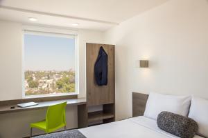 een slaapkamer met een bed, een bureau en een raam bij One Ciudad de Mexico La Raza in Mexico-Stad