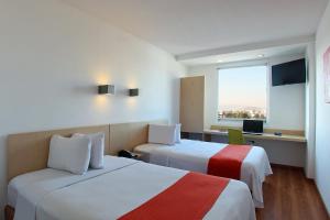 a hotel room with two beds and a desk at One Queretaro Plaza Galerias in Querétaro +70 photos