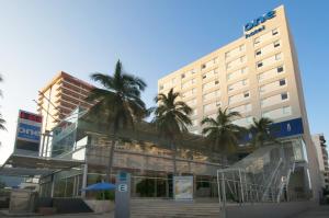 um edifício de hotel com palmeiras em frente em One Acapulco Costera em Acapulco