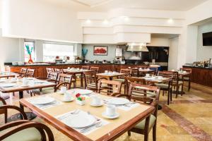 a restaurant with wooden tables and chairs and a kitchen at Fiesta Inn Chihuahua in Chihuahua