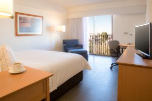 a hotel room with a bed and a desk and a television at Fiesta Inn Chihuahua in Chihuahua