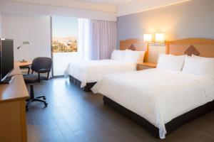 um quarto de hotel com duas camas e uma secretária e uma televisão em Fiesta Inn Chihuahua em Chihuahua