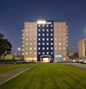 un bâtiment d'hôtel avec une pelouse devant lui dans l'établissement One San Luis Potosi Glorieta Juarez, à San Luis Potosí