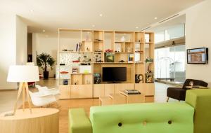 a living room with a green couch and a television at Fiesta Inn Periferico Sur in Mexico City