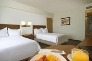 um quarto de hotel com duas camas e um prato de fruta numa mesa em Fiesta Inn Puebla Finsa em Puebla