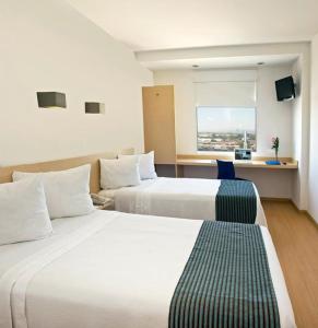 Habitación de hotel con 2 camas y ventana en One Aguascalientes San Marcos en Aguascalientes