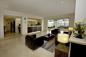 a lobby with chairs and a table in a building at One Aguascalientes San Marcos in Aguascalientes