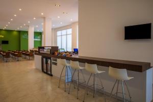 a lobby with a bar with stools and a television at One Chihuahua Fashion Mall in Chihuahua