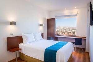 a hotel room with a bed and a window at One Chihuahua Fashion Mall in Chihuahua