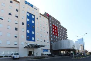 un edificio de hotel con un letrero rojo y azul en One Queretaro Centro Sur en Querétaro