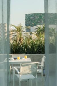 une table et des chaises blanches avec deux oranges sur la table dans l'établissement Fiesta Inn Merida, à Mérida