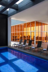 a swimming pool with lounge chairs and a building at Fiesta Inn Morelia Altozano in Morelia