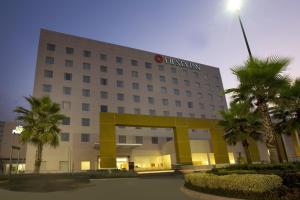 un bâtiment d'hôpital avec des palmiers devant lui dans l'établissement Fiesta Inn Tepic, à Tepic