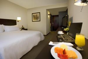 een hotelkamer met een bed, een laptop en een bord eten bij Fiesta Inn Tepic in Tepic