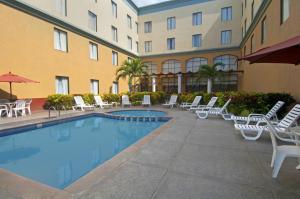 a hotel with a pool and chairs and a building at Fiesta Inn Poza Rica in Poza Rica de Hidalgo