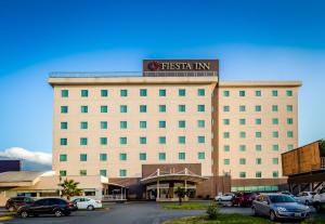 a hotel with cars parked in a parking lot at Fiesta Inn Monterrey Fundidora in Monterrey